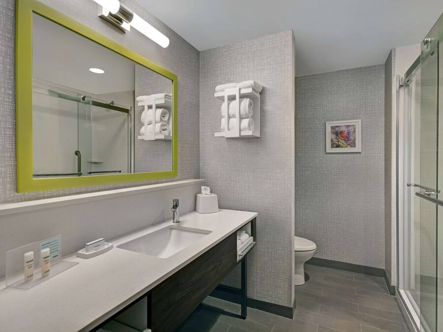 Un baño moderno con un espejo grande, un lavabo, un inodoro y una zona de ducha.