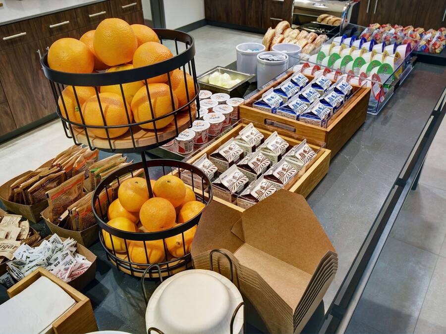 A breakfast buffet with oranges, pastries, and packaged goods.