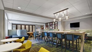 A modern hotel lobby with a bar area, seating arrangements, and a television mounted on the wall. - Hampton Inn Cave City, KY (Cave City)