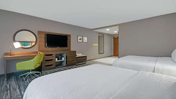 A hotel room with a large bed, a desk with a chair, a television, and a mirror.