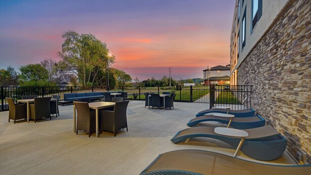 An outdoor patio area with seating arrangements, a stone wall, and a view of the sky. - Hampton Inn Cave City, KY (Cave City)