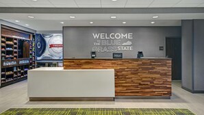 A hotel reception area with a modern design, featuring a reception desk, a wall with a welcome sign, and a display of amenities.