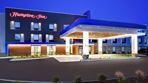 A Hampton Inn hotel with a modern design, featuring a prominent neon sign, a covered entrance, and a landscaped front area. - Hampton Inn Cave City, KY (Cave City)