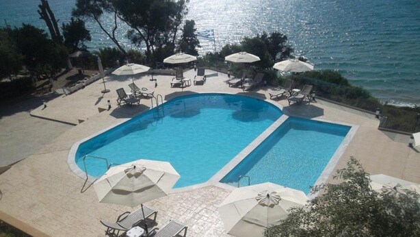 Ein rechteckiger Swimmingpool mit zwei Bereichen, umgeben von Liegestühlen und Sonnenschirmen.