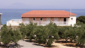 Ein zweistöckiges Gebäude mit rotem Ziegeldach, einem Balkon mit weißen Geländern und Blick auf das Meer.