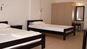 Ein Hotelzimmer mit zwei Einzelbetten, einem Holzschrank, einem Schreibtisch mit Stuhl und einem Spiegel.