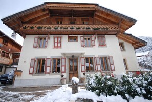 A traditional wooden chalet with a symmetrical facade, multiple windows with shutters, and a snow-covered entrance. - Chalet Abbaye (Saint-Jean-d'Aulps)