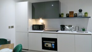 Eine moderne Küche mit weißen Schränken, einer eingebauten Mikrowelle, einer Kaffeemaschine und einem kleinen Backofen.