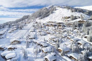 Un villaggio innevato con chalet in legno e una pista da sci.