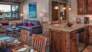 Una cocina amplia con armarios de madera, encimeras de granito e iluminación colgante.