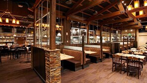 Un restaurante con vigas de madera, pilares de piedra y varias zonas de estar, incluyendo cabinas y mesas.