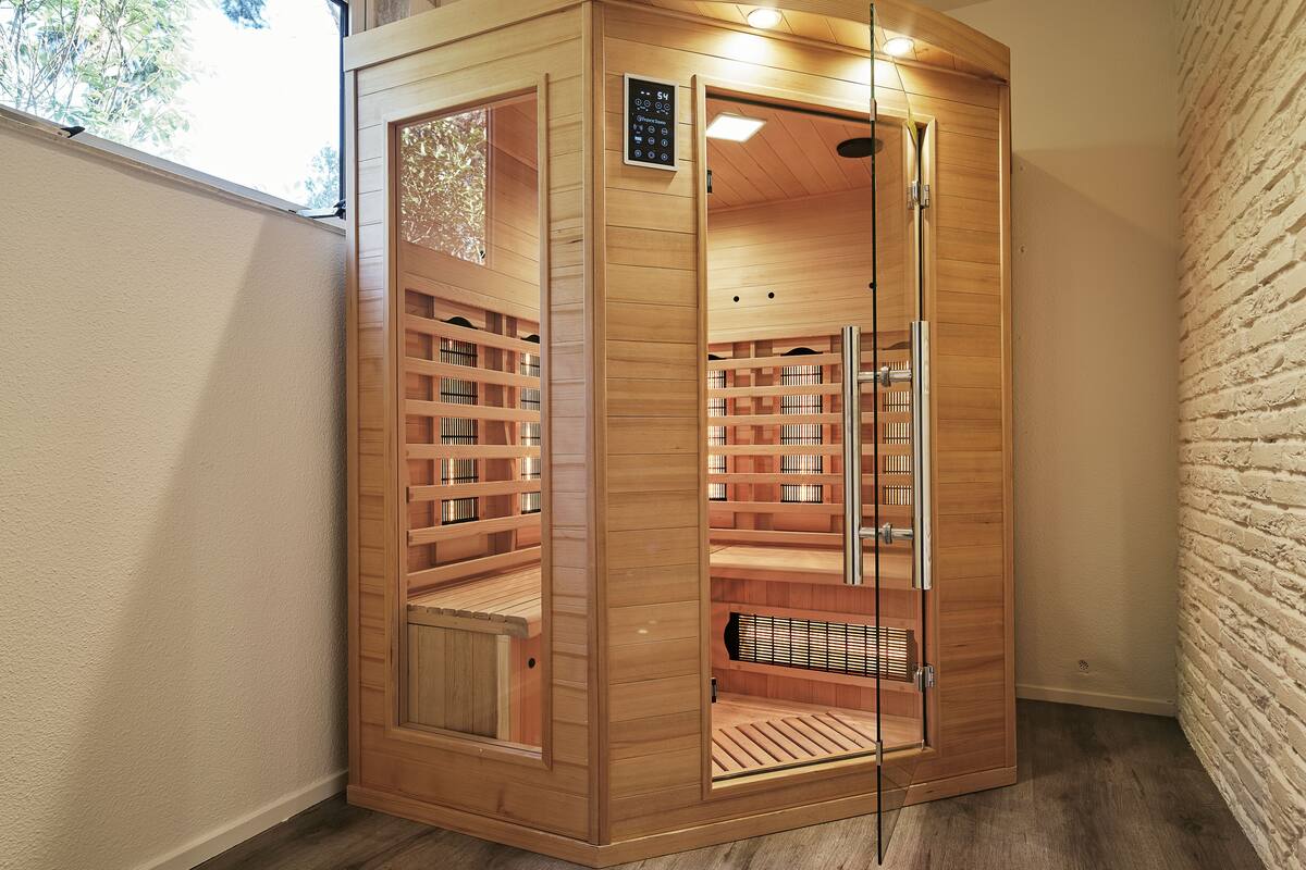 A sauna with wooden walls, a glass door, and a bench inside.