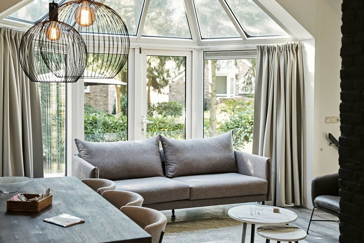 A modern living room with a grey sofa, a round coffee table, and a dining table with chairs.