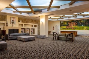 A spacious lobby with a patterned carpet, sofas, a fireplace, and a large painting of wildlife. - Pegasos World Side (Manavgat)