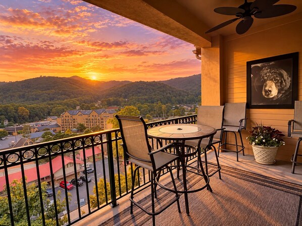 A balcony with a table and chairs, a ceiling fan, and a framed picture of a dog.