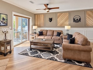 A living room with a brown leather sofa, a wooden coffee table, and a ceiling fan. - Downtown Gatlinburg Luxury Penthouse, Mountain Views & 2 Balconies (Gatlinburg)