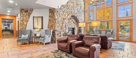 A lobby with a stone wall, leather sofas, and a fireplace.