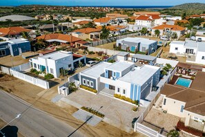 A residential area with modern houses, a swimming pool, and a clear view of the ocean.