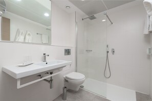Une salle de bain moderne avec une douche à parois de verre, un lavabo blanc et des toilettes.