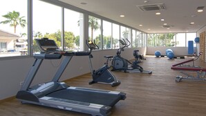 Uma academia com esteiras, bicicletas ergométricas e bolas de exercício.