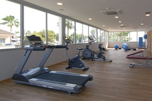 A gym with treadmills, stationary bikes, and exercise balls.
