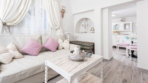 A cozy living room with a sofa, a table, and a kitchen area in the background.