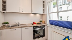 A modern kitchen with white cabinets, a built-in oven, and a window with a view of a building.