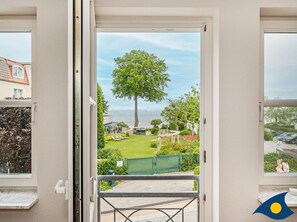 A view from a balcony with a large tree, a lawn, and a body of water in the background. - Rolandseck II, Whg. 07 - RO II 07 (Heringsdorf)