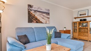 A living room with a blue sofa, a wooden coffee table, a floor lamp, a painting, and a wooden cabinet.