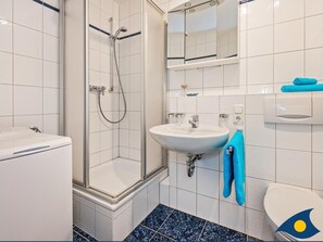 Une salle de bain avec une douche à parois de verre, un lavabo et des toilettes.