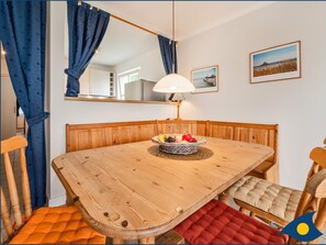 Un coin repas avec une table en bois, des chaises, un panier de fruits, une lampe et un miroir.