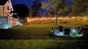 Ein Garten mit Holzterrasse, Sitzgelegenheiten und Lichterketten.