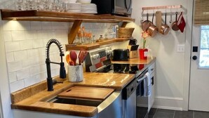 Eine moderne Küche mit Holzarbeitsplatte, Edelstahlgeräten und einem eingebauten Backofen.