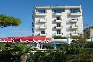 A multi-story hotel with balconies, a swimming pool, and red umbrellas. - Ruhl Beach Hotel (Jesolo)