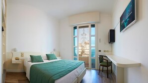 A bedroom with a bed, green pillows, a desk, and a chair. - Ruhl Beach Hotel (Jesolo)