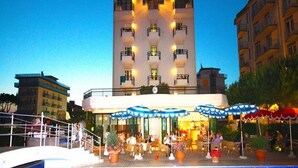 A hotel with a central courtyard, outdoor seating, and a clock tower. - Ruhl Beach Hotel (Jesolo)