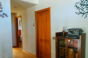 A hallway with a wooden door, a bookshelf with books, and a decorative wall piece.