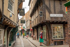A narrow street lined with traditional half-timbered buildings, including a shop named 'Little Shambles' with a display window. - 6 Longfield Terrace · Elegant, Modern 5 Bed House with Free Parking - Pass The Keys (York)