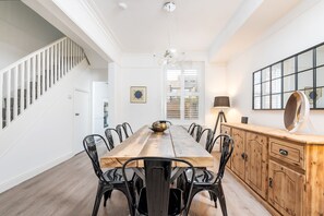 A dining area with a long wooden table, black metal chairs, and a wooden cabinet with drawers. - 6 Longfield Terrace · Elegant, Modern 5 Bed House with Free Parking - Pass The Keys (York)