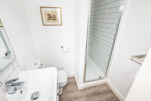A modern bathroom with a white sink, toilet, and glass shower enclosure. - 6 Longfield Terrace · Elegant, Modern 5 Bed House with Free Parking - Pass The Keys (York)