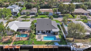 A residential area with a large house featuring a swimming pool, a dock with a boat, and a well-maintained lawn. - Villa by the Sea🌴  🌊  Luxury Coastal Retreat - 5 Minute walk to beach (Lauderdale by the Sea)