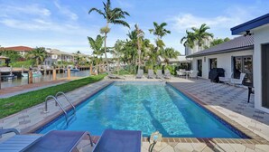 A swimming pool with lounge chairs, a dock with boats, and palm trees. - Villa by the Sea🌴  🌊  Luxury Coastal Retreat - 5 Minute walk to beach (Lauderdale by the Sea)