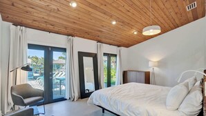 A bedroom with a bed, a chair, a lamp, and a view of the outside. - Villa by the Sea🌴  🌊  Luxury Coastal Retreat - 5 Minute walk to beach (Lauderdale by the Sea)