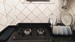 A kitchen with a gas stove, a window, and a dish rack. - TC202 Paraíso na Praia (Rio de Janeiro)