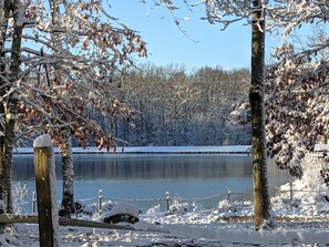 Un paysage hivernal paisible, avec un lac gelé, des arbres couverts de neige et une clôture en bois.