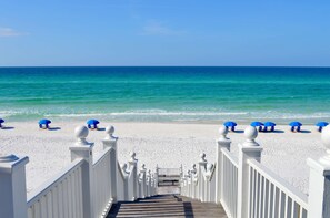 A wooden staircase leading to a beach with white railings and blue umbrellas. - 6 Houses to Beach in Seaside, Screened Porch, Steps to Restaurants + 2 Bikes! (Santa Rosa Beach)