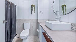 A modern bathroom with a toilet, sink, and shower curtain. - Ocean View 49A Wi-Fi Pool King bed (Airlie Beach)