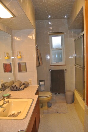 A compact bathroom with a toilet, sink, and a shower area.