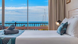 A hotel room with a bed, a view of the sea, and a balcony with a railing. - OCEAN VIEWS 10A pool & Spa Wi-Fi (Airlie Beach)