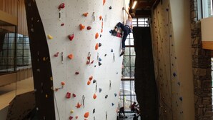 A climbing wall with various holds and a person climbing. - Family-Friendly Canmore Crossing Condo | Mountain Views | Sleeps 7 (Canmore)